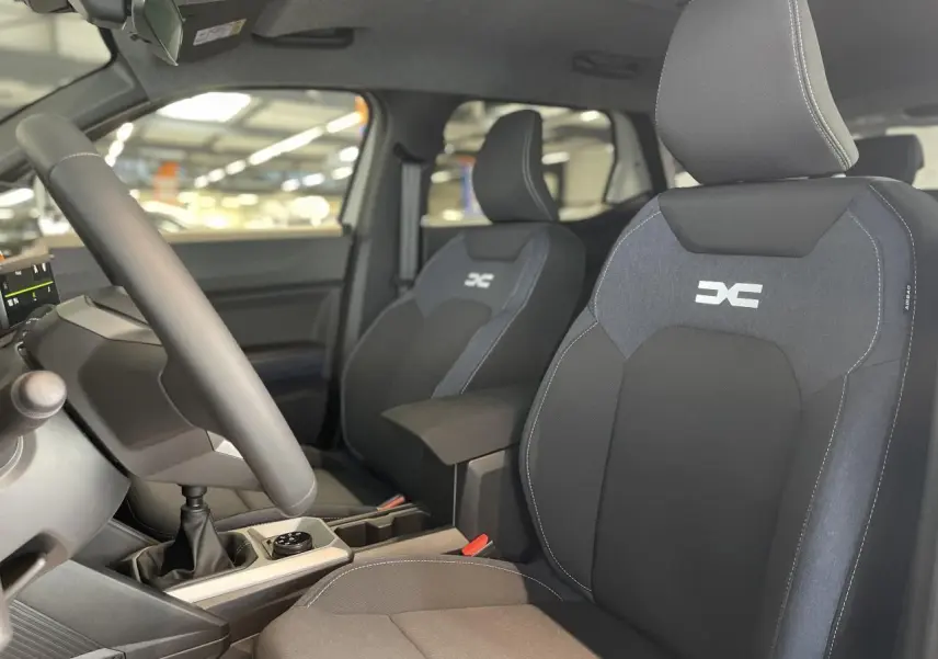 Intérieur du Dacia Duster 2025 vue côté conducteur, sièges en tissu Denim bleu avec logo Dacia brodé.