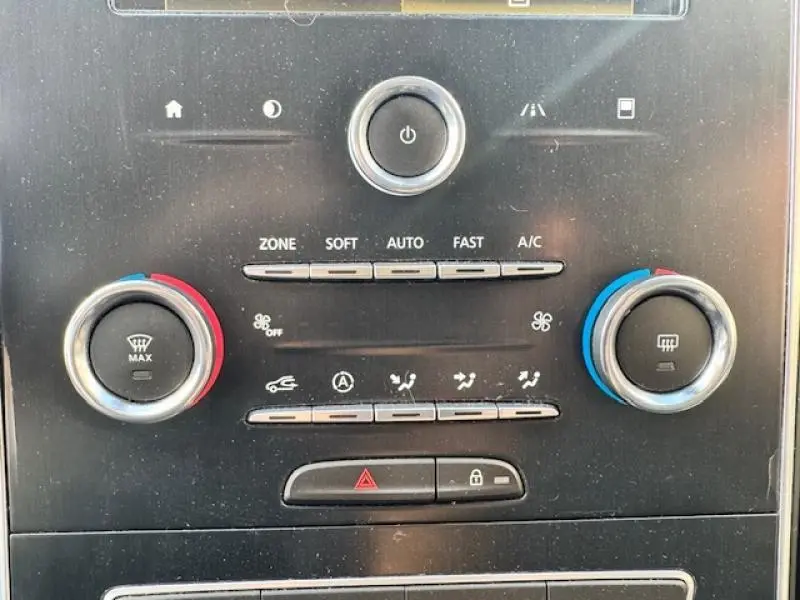 Gros plan sur la console centrale noire du Renault Grand Scenic 2019 montrant les commandes de climatisation et de verrouillage.