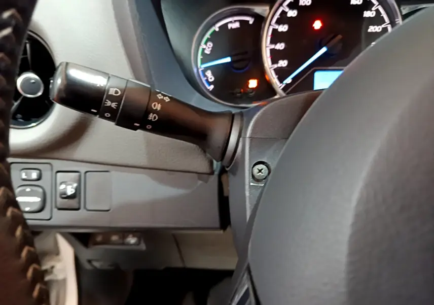 Vue intérieure centrée sur le commodo gauche et le tableau de bord éclairé de la Toyota Yaris hybride 2020.