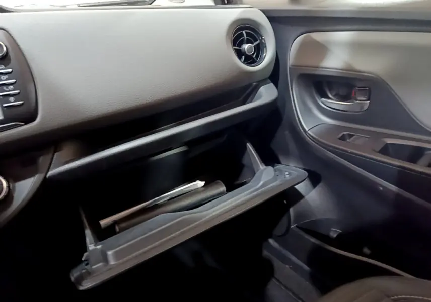 Vue intérieure côté passager de la Toyota Yaris 1.5 Hybride 2020, boîte ouverte et tableau de bord gris foncé.