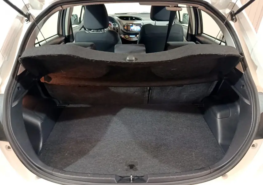 Vue arrière du coffre ouvert d'une Toyota Yaris blanche, montrant l'espace de chargement et l'intérieur des sièges avant.