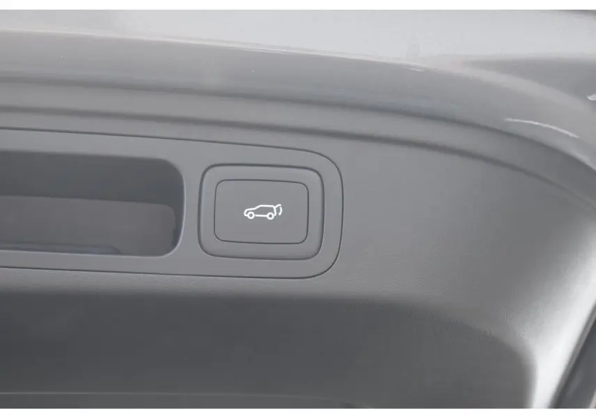 Bouton de hayon électrique avec pictogramme blanc, situé à l'intérieur du coffre d'un MG Motor EHS gris.