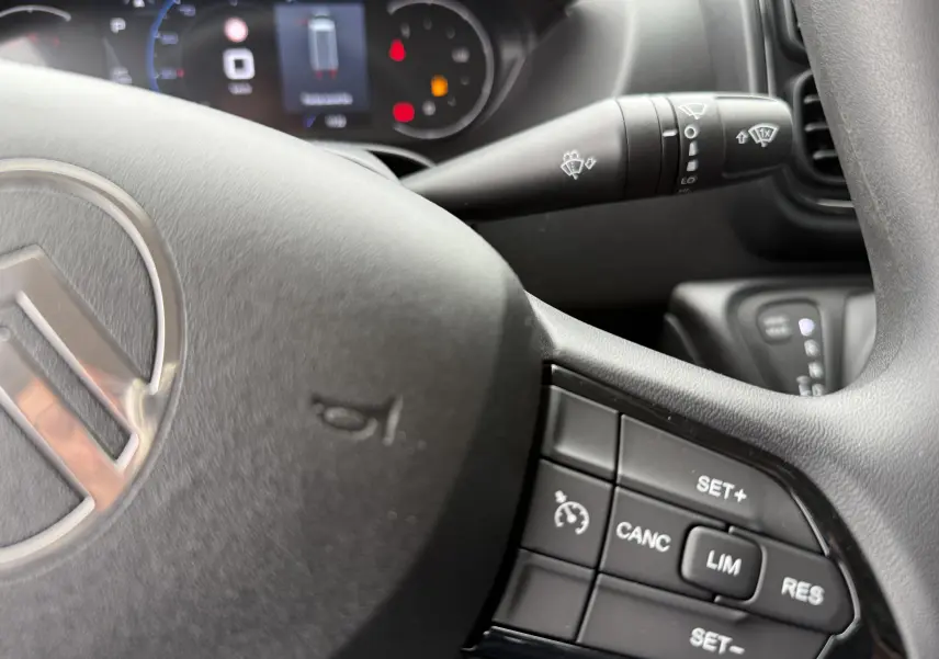 Gros plan sur le volant noir du Citroën Jumper 2025 avec commandes de régulateur et tableau de bord flou en arrière-plan.