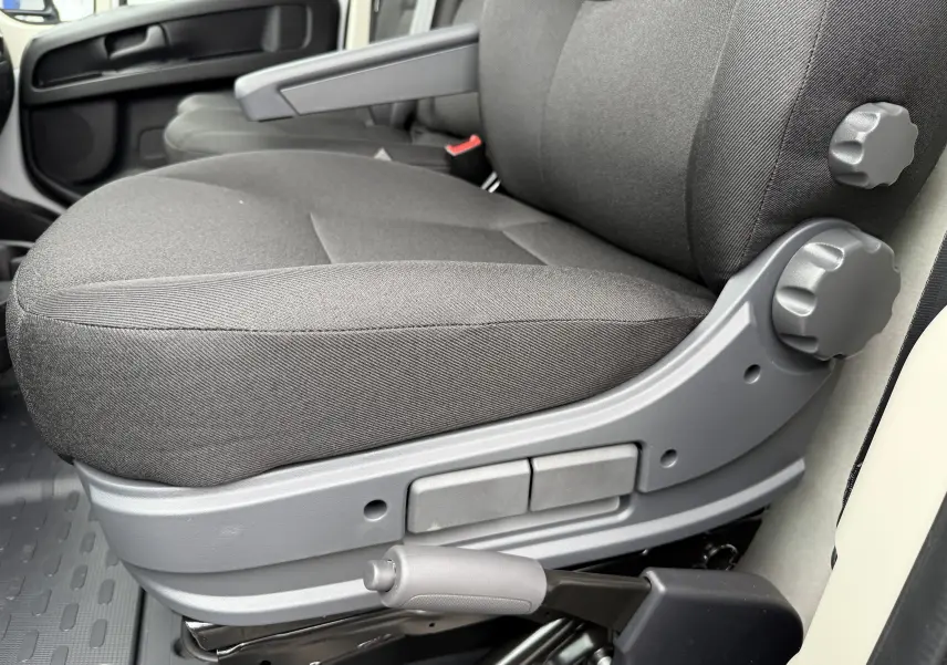 Gros plan sur le siège conducteur en tissu gris foncé du Citroën Jumper L3H2 2025, avec réglages manuels visibles.