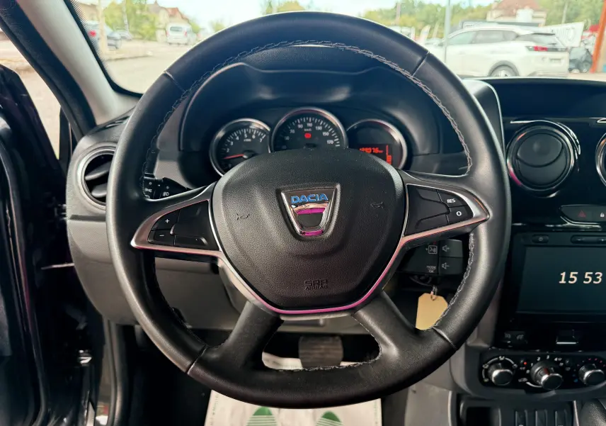 Vue rapprochée du volant en cuir noir du Dacia Duster 2017, avec tableau de bord et commandes visibles.