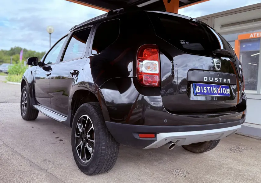 Vue 3/4 arrière gauche d'un Dacia Duster noir métal 2017 avec jantes bi-ton et badge DUSTER sur le hayon.