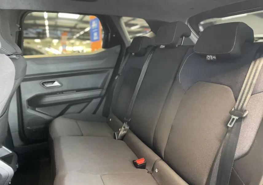 Vue intérieure de la banquette arrière noire du Dacia Duster 2025 avec ceintures et appuie-têtes intégrés.