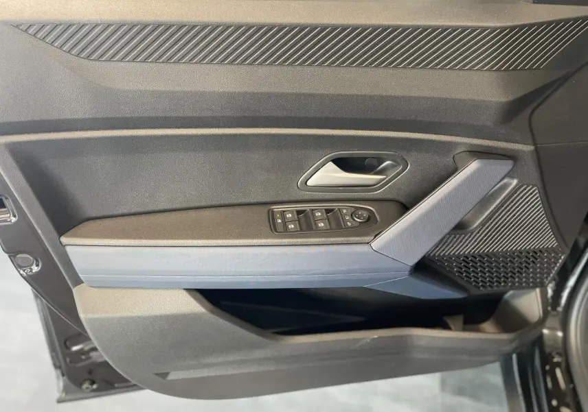 Intérieur côté gauche de la porte avant d'un Dacia Duster 2025 noir métallisé avec commandes de vitres et accoudoir Denim bleu.