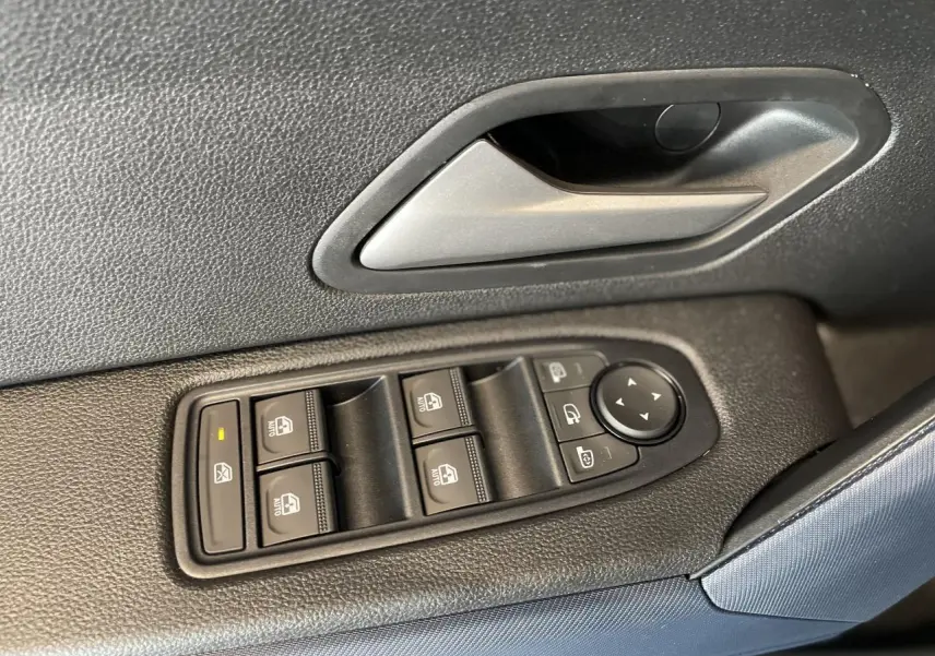 Gros plan sur la commande des vitres électriques et la poignée intérieure côté gauche du Dacia Duster 2025 finition Journey.