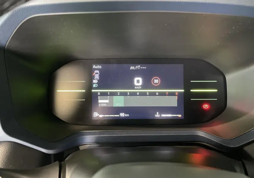 Tableau de bord digital du Dacia Duster 2025 affichant la vitesse à 0 km/h et indicateurs de sécurité allumés.