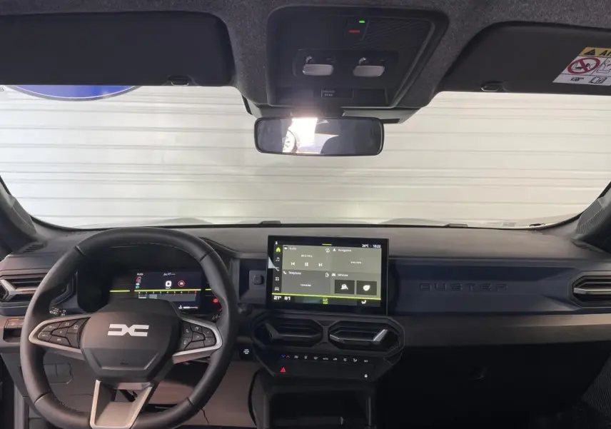 Vue frontale de l'habitacle du Dacia Duster 2025 noir métallisé, avec tableau de bord digital et écran tactile central.