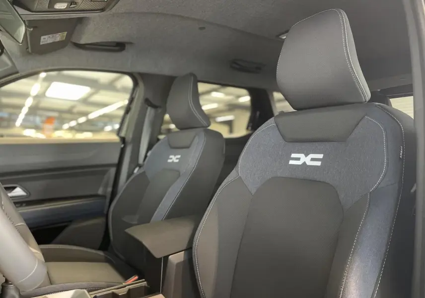 Gros plan sur les sièges avant en sellerie Denim bleu et noir du Dacia Duster 2025, avec logo DC brodé.