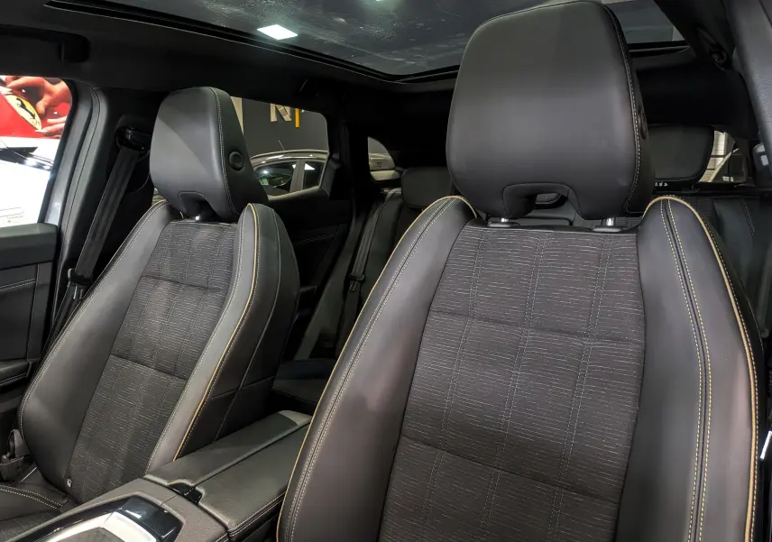 Gros plan sur les sièges avant en cuir noir et tissu gris avec surpiqûres jaunes du Renault Austral E-TECH 2024.