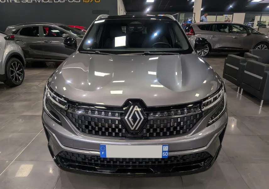 Vue frontale d'un Renault Austral E-TECH Full Hybrid gris schiste, avec calandre noire à damier et logo Renault central.