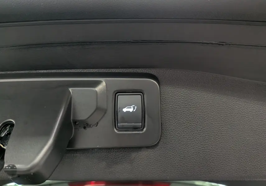Bouton d'ouverture du coffre sur la garniture intérieure d'un Renault Austral gris Schiste 2024 E-TECH Full Hybrid.