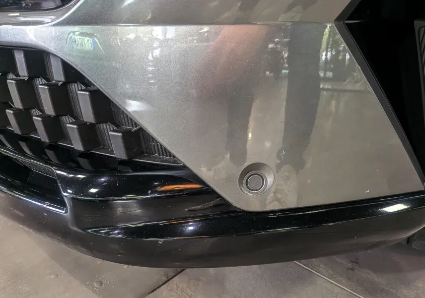 Détail du pare-chocs avant gris schiste du Renault Austral E-TECH avec capteur de stationnement intégré.