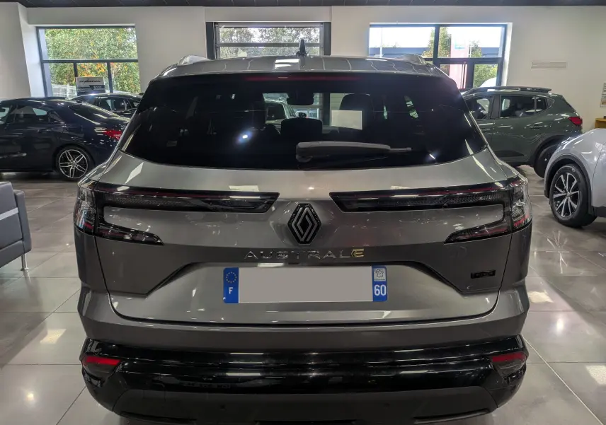 Vue arrière d'un Renault Austral gris schiste en showroom, avec feux arrière fins et logo central lumineux.