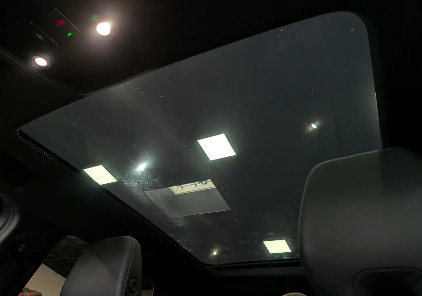 Toit panoramique en verre vu de l'intérieur du Renault Austral E-TECH gris, avec éclairage intérieur allumé.