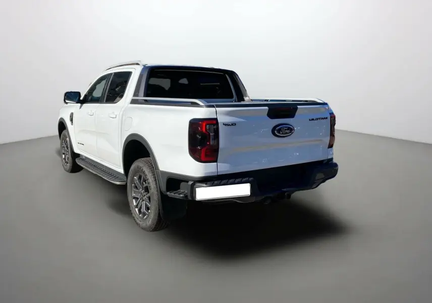 Ford Ranger 2.0 205 Wildtrak Plus blanc glacier vu en 3/4 arrière droit avec logo et feux arrière distinctifs.