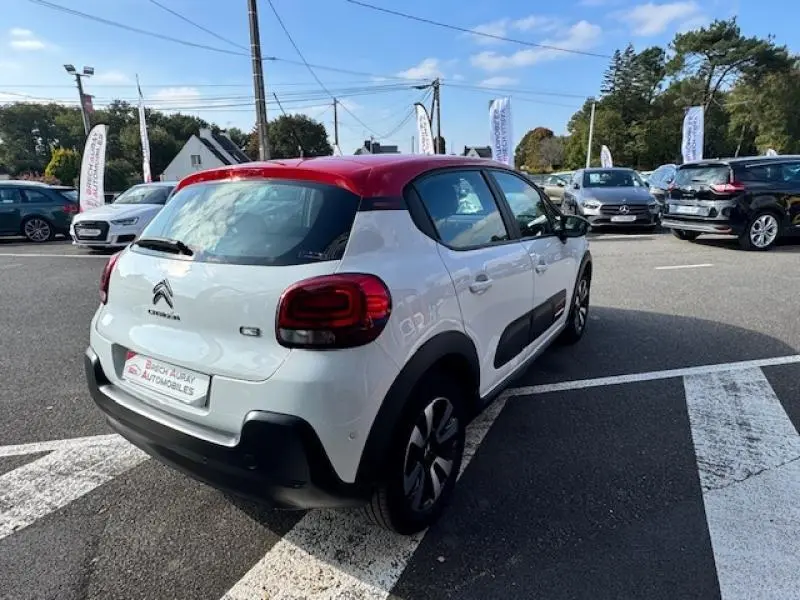 Citroën C3 1.2 Shine vue 3/4 arrière droit, blanc banquise avec toit rouge aden et jantes alliage noires.