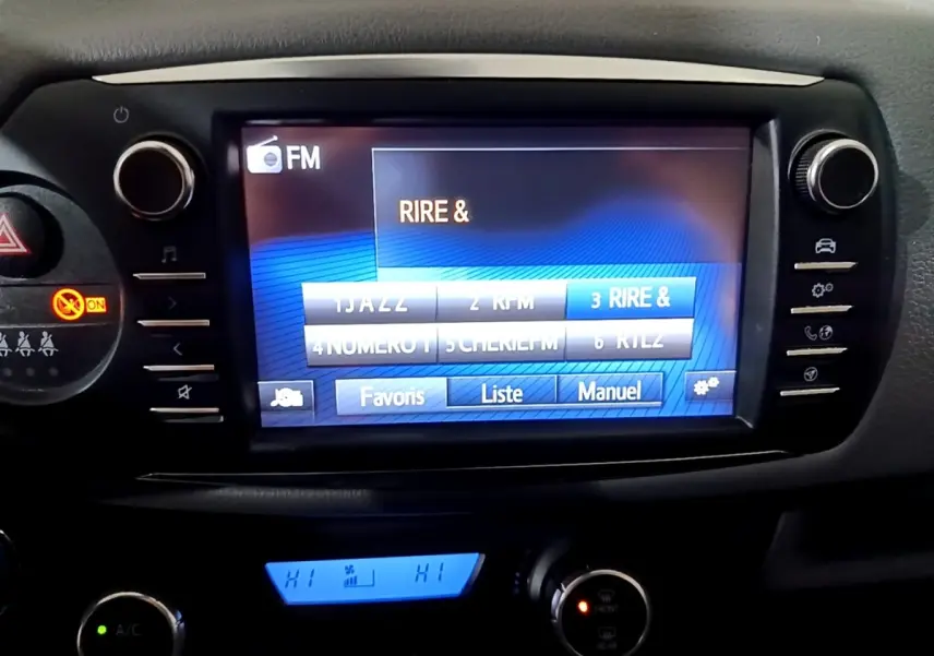 Vue rapprochée de l’écran tactile central multimédia de la Toyota Yaris 2019 avec commandes climatisation et boutons latéraux.