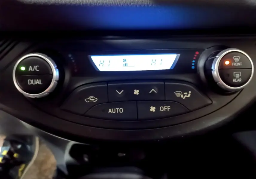 Panneau de commande de la climatisation 2 zones de la Toyota Yaris blanche, affichage digital avec boutons rotatifs.