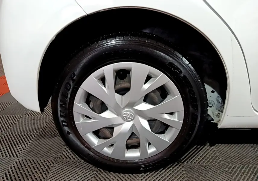 Gros plan sur la roue arrière droite blanche d'une Toyota Yaris 1.5 VVT-I Hybrid avec enjoliveur argenté.