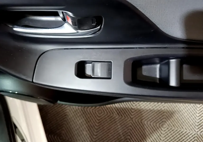 Gros plan sur la commande de lève-vitre côté conducteur de la Toyota Yaris blanche 2019, intérieur noir.