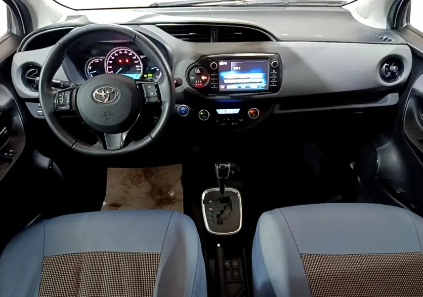 Vue intérieure avant de la Toyota Yaris 1.5 Hybrid 2019, volant cuir alu multifonctions et écran tactile central.