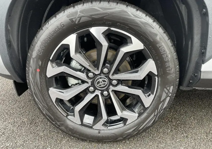 Gros plan sur la roue avant droite avec jante alliage bicolore noir et argent du Toyota Yaris Cross gris clair 2026.