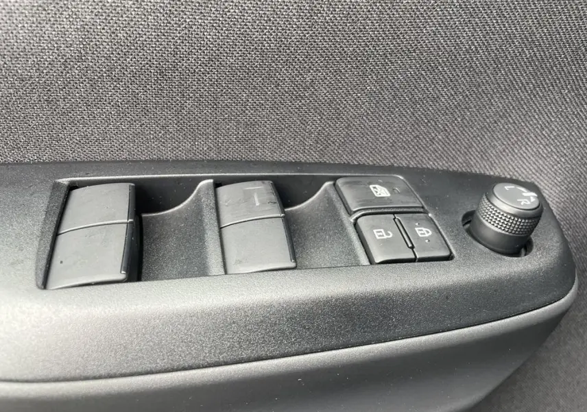 Gros plan sur les commandes de lève-vitres et rétroviseurs côté conducteur de la Toyota Yaris Cross gris clair.