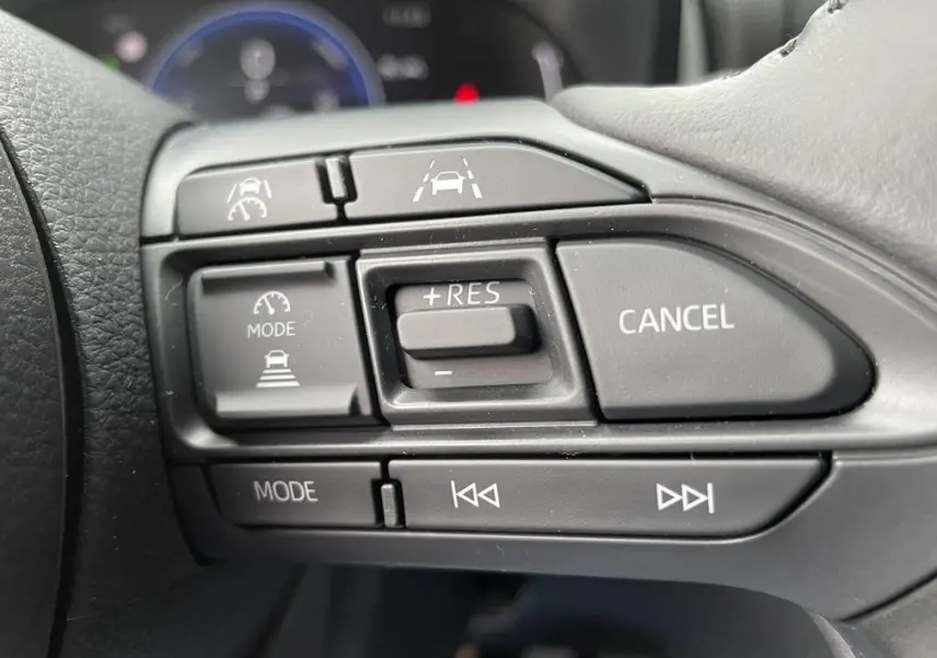 Gros plan sur les commandes multifonctions du volant gris foncé de la Toyota Yaris Cross 2026, version hybride.