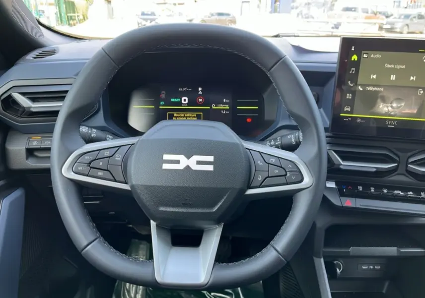 Vue rapprochée du volant cuir noir du Dacia Bigster Hybrid 155 Expression Plus avec tableau de bord digital et écran central tactile.