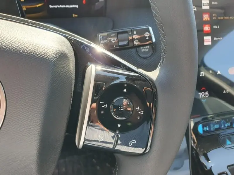 Gros plan sur les commandes multifonctions du volant du Citroën C5 Aircross 1.2 Hybride, finition noire brillante.
