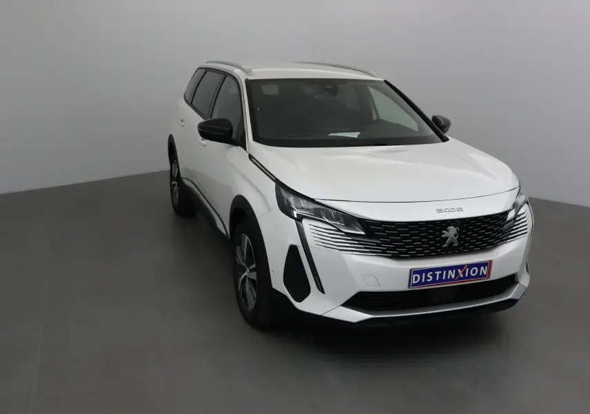Peugeot 5008 blanc nacré en 3/4 avant droit, avec calandre noire et feux LED distinctifs visibles.