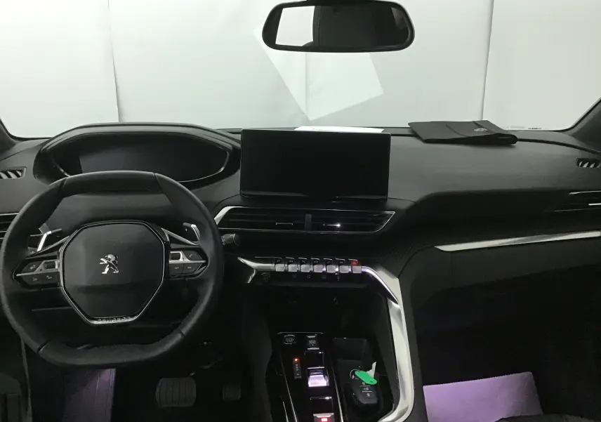 Vue intérieure du tableau de bord et volant du Peugeot 5008 blanc nacré 2024, avec écran tactile et commandes modernes.