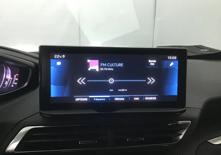 Écran central tactile du tableau de bord du Peugeot 5008 2024 affichant une radio FM sur fond noir.