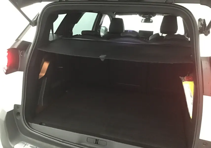 Coffre ouvert du Peugeot 5008 blanc nacré 2024, vue arrière montrant l'espace de chargement et la tablette cache-bagages.