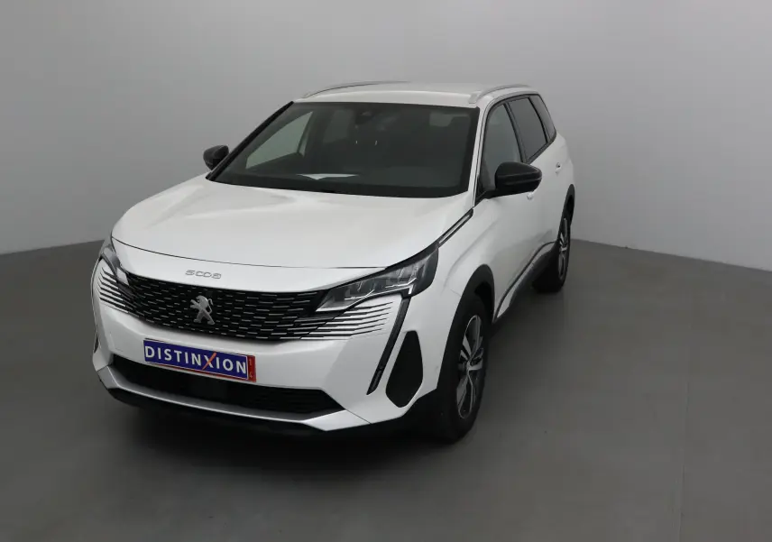 Peugeot 5008 blanc nacré en 3/4 avant droit, avec calandre noire et jantes alliage 18 pouces visibles.
