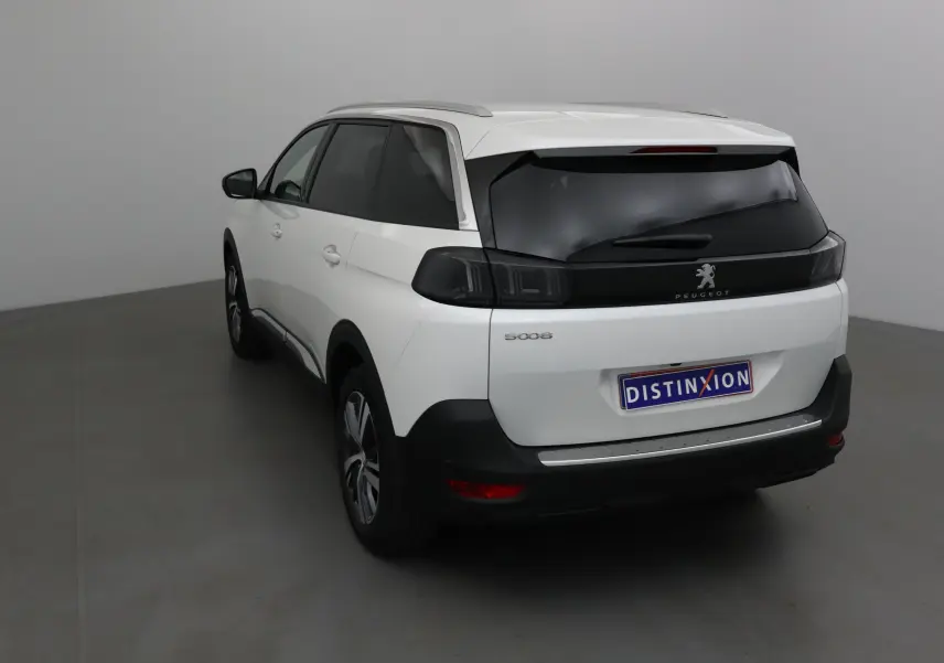 Vue 3/4 arrière gauche d'un Peugeot 5008 blanc nacré avec vitres teintées et feux arrière noirs.