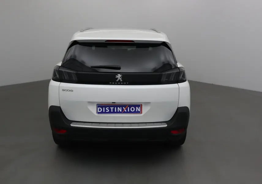 Vue arrière d'un Peugeot 5008 blanc nacré 2024 avec feux arrière noirs et logo central sur hayon.