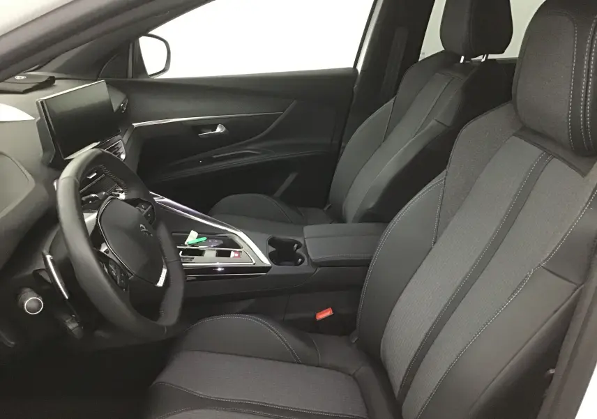 Intérieur avant droit du Peugeot 5008 2024 avec sièges tissu et cuir gris, volant multifonction et écran tactile central.