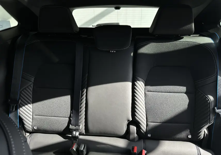 Vue arrière intérieure des sièges arrière noirs avec surpiqûres bleues du Renault Symbioz Esprit Alpine 2025.
