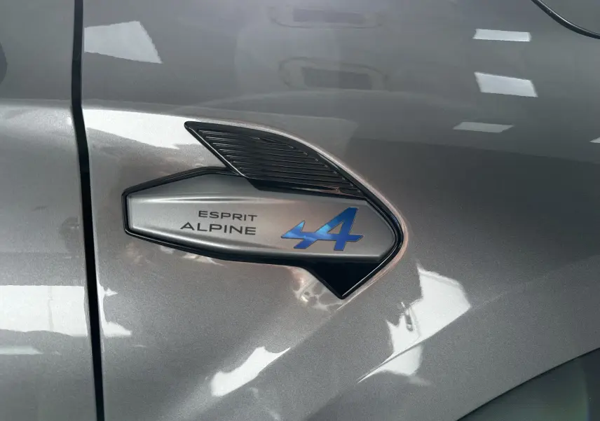 Détail de l'aile avant gauche gris Cassiopée du Renault Symbioz avec logo Esprit Alpine bleu et noir.