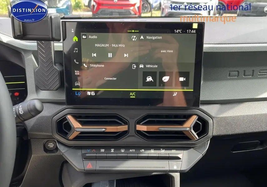 Tableau de bord du Dacia Duster 2025 avec écran tactile et aérateurs couleur cuivre, vue frontale intérieure.