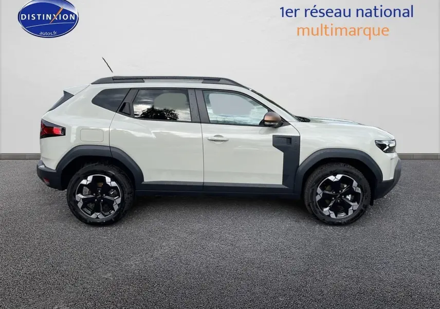 Profil droit du Dacia Duster 2025 Sandstone avec jantes noires et barres de toit noires visibles.