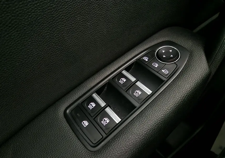 Gros plan sur les commandes électriques des vitres et rétroviseurs côté conducteur du Renault Captur gris Highland/Noir 2024.