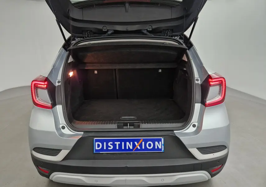 Vue arrière du Renault Captur gris Highland avec coffre ouvert et feux arrière allumés dans un studio.