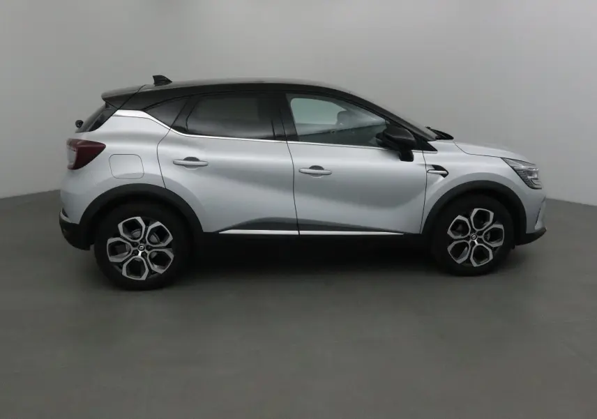 Profil droit du Renault Captur 2024 gris Highland avec toit noir et jantes alliage 18 pouces dans un studio.