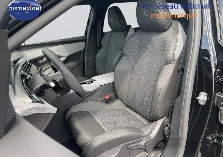Intérieur du Peugeot 5008 Hybrid 136ch GT 2025, vue côté conducteur, sièges cuir noir et tissu gris avec logo Peugeot brodé.